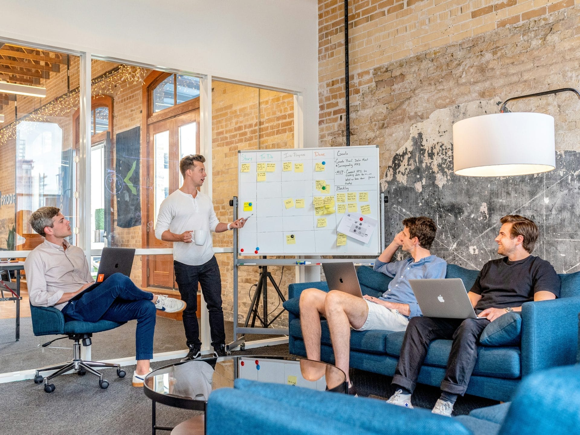 Team meeting in a modern office with a presenter explaining notes on a whiteboard.
