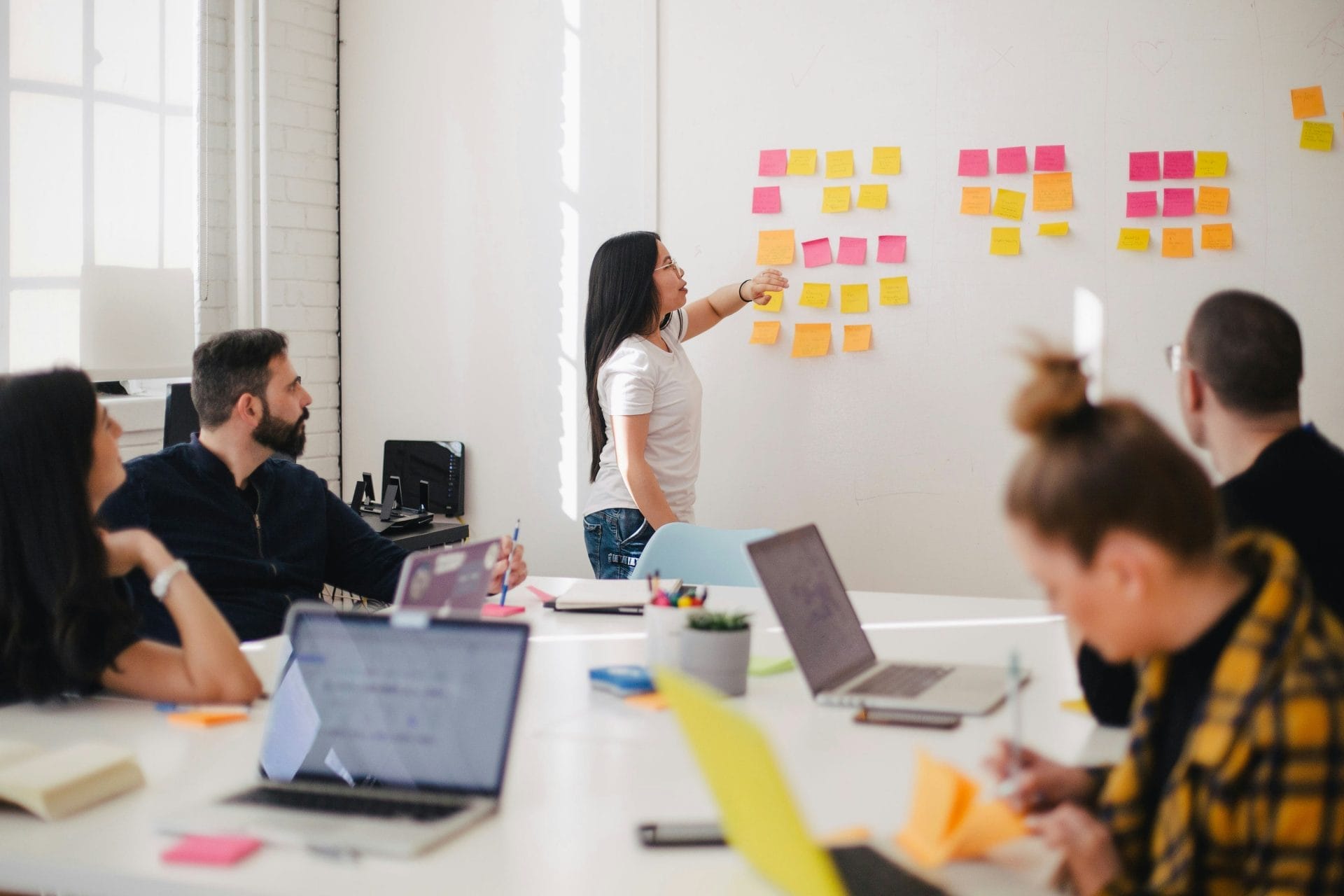 a woman pointing at sticky notes on a wall